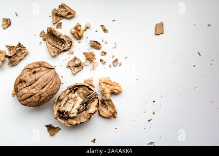 Cracked and whole walnuts on a white background, with a scattered shallow shell, in natural light from the window. Close-up. Stock Photo