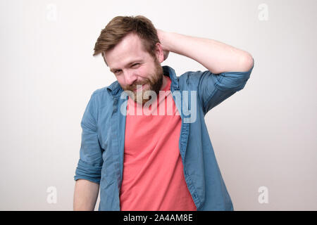 A bearded man looks at the camera slyly smiles and narrowing one eye. Isolated on a white background. Close-up. Stock Photo