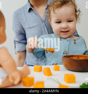 The little girl is trying to reach out to the dolls, wants her to feed Stock Photo