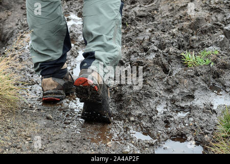 Walker/hiker's lower half of legs and hiking boots, walking through mud Stock Photo