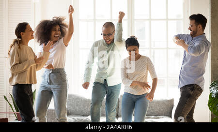 Happy diverse friends dancing at home party, having fun Stock Photo