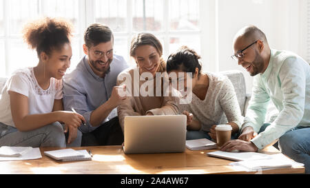 Happy diverse friends watching funny video, using laptop, having fun Stock Photo