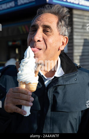 Bournemouth, UK. 13th October 2019, A man enjoys a huge ice cream while enjoying the glorious Autumnal sunshine with blue skies over Bournemouth Seafront after stormy weather this morning.Credit: Keith Larby/Alamy Live News Stock Photo