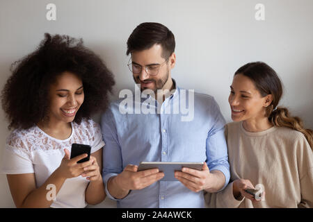 Happy diverse friends using devices, playing mobile phone game together Stock Photo