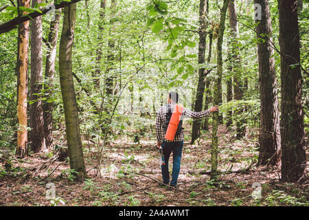 Man with Backpack and map searching directions in wilderness area. Tourist with backpack using map in forest. concept tourism holidays. Hiking man Stock Photo