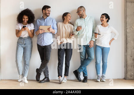 Happy diverse people using phones, laughing, having fun together Stock Photo
