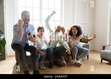 Excited diverse friends, football fans celebrating victory goal at home Stock Photo