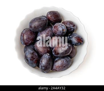 Purple damson plums in bowl top view isolated on white background with clipping path Stock Photo