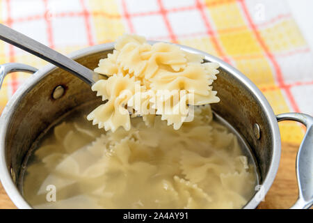 Boiled hot farfalle on the pasta spoon at home kitchen Stock Photo