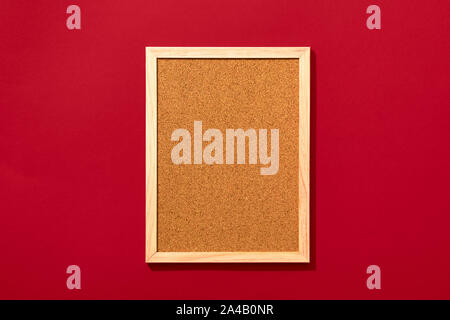 Empty cork board with wooden frame on red background, view from above with place for text. Stock Photo