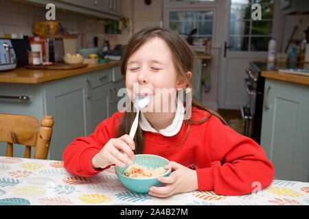 Young girl enjoying rice pudding at the kitchen table Stock Photo