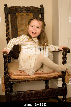 Female toddler sat on chair wearing her party dress