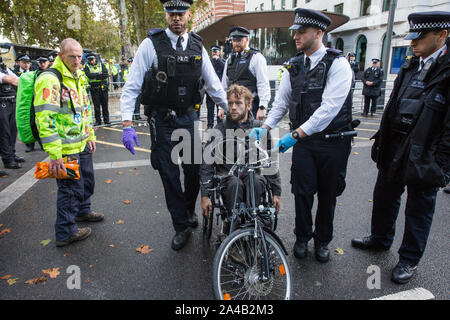 London, UK. 13 October, 2019. Police officers arrest a disabled climate activist from Extinction Rebellion using Section 14 of the Public Order Act 1986 during a protest outside New Scotland Yard against tactics employed by police officers which impinge on the right to protest of disabled activists, including the confiscation of wheelchair ramps, accessible toilets and tents. Credit: Mark Kerrison/Alamy Live News Stock Photo
