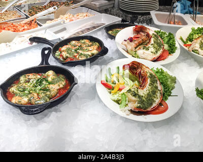 Cooked tasty seafood, big lobsters, prawns with fresh paprika, tomatoes and greens on bed of cold ice. Stock Photo