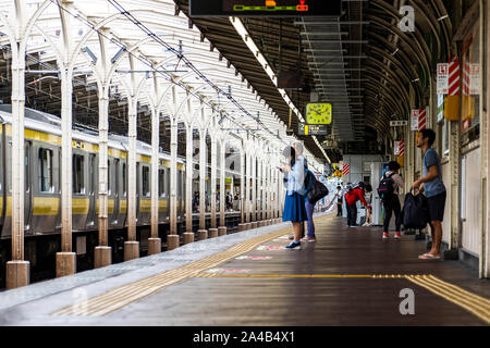 TOKYO, JAPAN - OCTOBER 8, 2018. People are on the Platform at a Train Station in Tokyo, Japan. Stock Photo