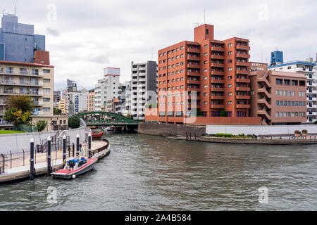 TOKYO, JAPAN - OCTOBER 8, 2018. Regular View Of Japanese Skyline and Sumida River in Tokyo. Residential Building and Parked Boats at the Riverfront. Stock Photo