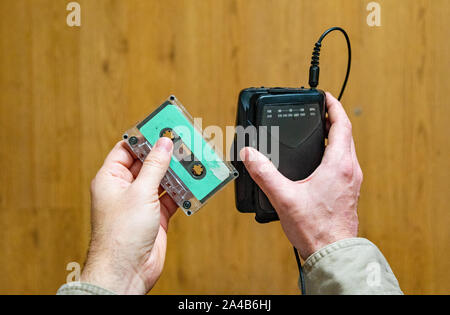 Mans hands incerting cassette tape into portable tape machine, vintage electonics imagery Stock Photo