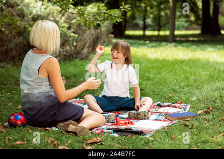 Little boy with Down syndrome playing with his loving mother outdoors Stock Photo