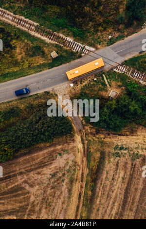Aerial view of road and railway intersection with bus and car crossing rails Stock Photo