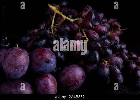 fresh blue plums and grapes on a black reflective background Stock Photo