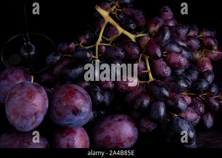fresh blue plums and grapes on a black reflective background Stock Photo