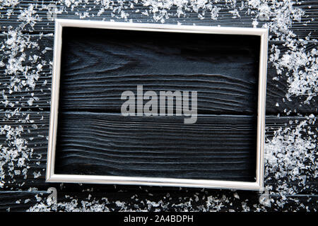 Christmas background, silver white snowflakes on black wooden table. Silver frame with free space. Space fo text. Top view. Stock Photo