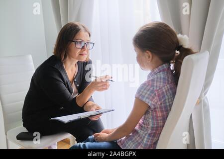 Talking girl and woman psychotherapist in office near window. Child psychology, mental health Stock Photo
