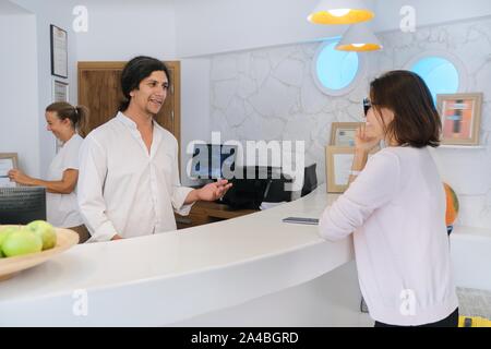 Reception at the resort hotel. Man and woman receptionists at the workplace. Guest checking in at the front desk Stock Photo