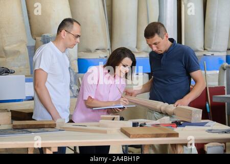 Group of industrial people client, designer or engineer and workers working together on project of wooden furniture. Teamwork in carpentry workshop. Stock Photo