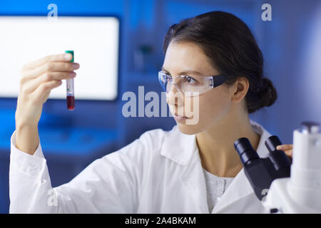 Portrait of young woman holding blood sample while doing medical research in laboratory, copy space Stock Photo