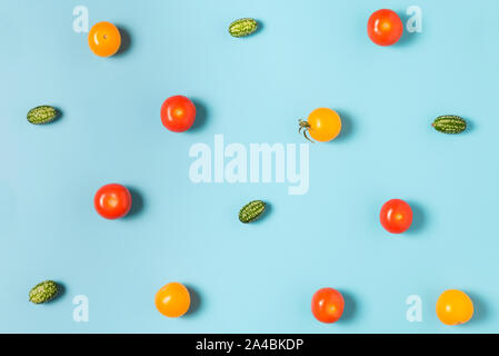 Colorful food pattern of mini cucumbers and yellow and red tomatoes on blue background. flat lay. top view Stock Photo