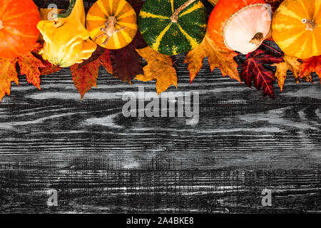 Thanksgiving or Halloween background. Autumn composition. Pumpkins with fall leaves on black wooden table. Flat lay. top view with copy space Stock Photo