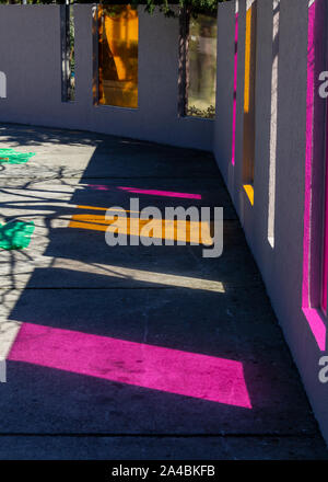 The colored glass of a fence creates colorful shadows on the ground Stock Photo