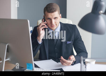 Displeased businessman sit at his desk while doing cold calls Stock Photo