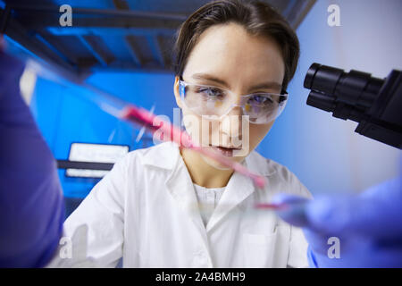 Fish eye view at young female scientist preparing test sample using dropper while working in medical laboratory, copy space Stock Photo