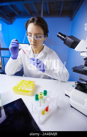 Portrait of young female scientist preparing test sample using dropper while working in medical laboratory Stock Photo