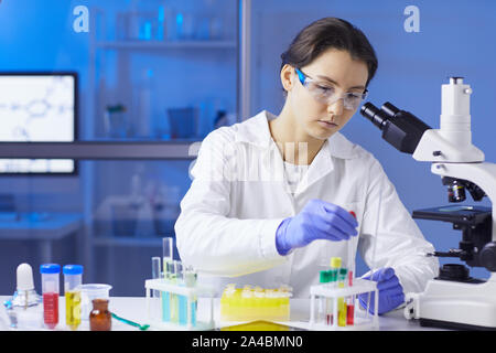 Portrait of young female scientist preparing test sample using dropper while working in medical laboratory, copy space Stock Photo
