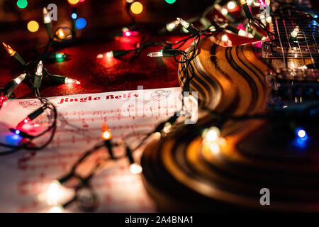 Guitar Music for the holiday season.  Jingle Bells sheet music and Christmas lights accompany a beautiful laminated wood electric guitar. Stock Photo