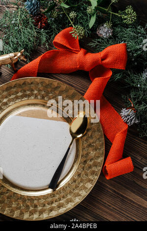 Holiday Gold place setting, table decorated with natural pine branches, and red lace on wooden background, from above. Ideas for the Christmas table o Stock Photo