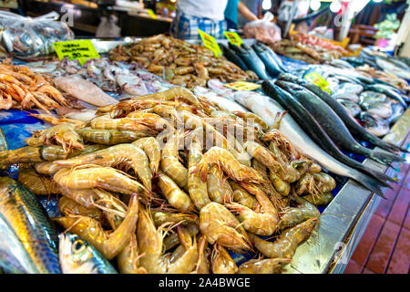 Portrait of salesman in apron offering female customer fresh fish at  seafood shop Stock Photo - Alamy