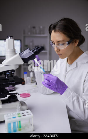 Portrait of beautiful young woman preparing test samples while using microscope in laboratory Stock Photo