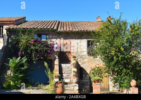 Traditional French stone farm house ready to welcome tourists on their summer holidays. Potted exotic cactus, citrus trees and purple bougainvillea. Stock Photo