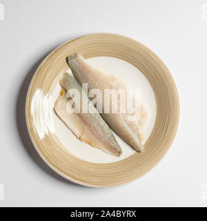 a dish with two fillets of sea bream on a white surface Stock Photo