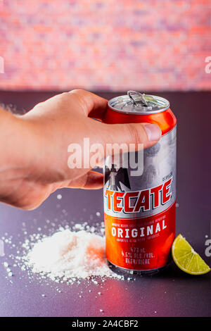 Person holding a Tecate beer can with salt and limes on the side on a vertical view Stock Photo