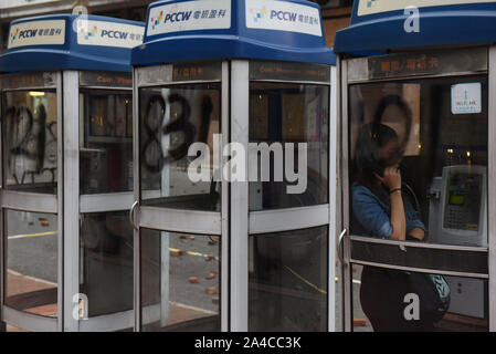 Hong Kong, China. 13th Oct, 2019. A woman uses a phone booth with 10.1 graffiti in reference to Chinese National Day on October 1st during the demonstration.Hong Kong's government introduced an anti-mask law which bans people from wearing masks at public assemblies which sparked outrage among the public. Hong Kong has been shaken for over four months of massive anti-government demonstrations. Credit: SOPA Images Limited/Alamy Live News Stock Photo