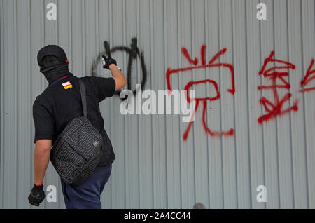 Hong Kong, China. 13th Oct, 2019. A protester writes slogans on the wall in Shatin during the demonstration.Hong Kong's government introduced an anti-mask law which bans people from wearing masks at public assemblies which sparked outrage among the public. Hong Kong has been shaken for over four months of massive anti-government demonstrations. Credit: SOPA Images Limited/Alamy Live News Stock Photo