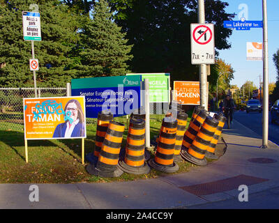 Orange bollards, a bus stop, cyclists and Federal election campaign posters make for a busy corner at Lakeview and Bronson, Ottawa, Ontario, Canada. Stock Photo