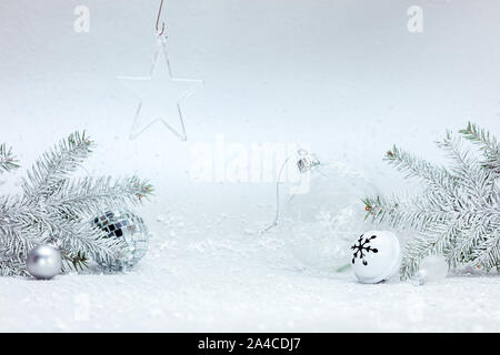 festive winter composition with christmas tree branches, various decorative balls and glass star on white snow background Stock Photo