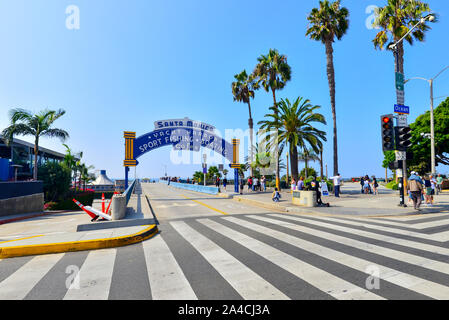 Entrance to Santa Monica Pier showing arched sign over the pier entrance and palm tree lined street Stock Photo