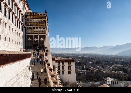 Lhasa, China - December 13 2018: Tourists walk up the stairs leading to the famous Potala Palace in Lhasa old town in Tibet province with the city in Stock Photo